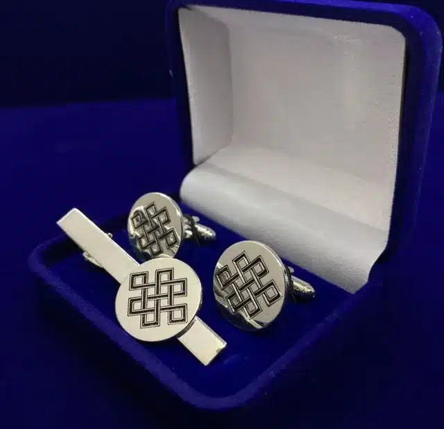 Gemelos y pasador de corbata plateados en un estuche azul
